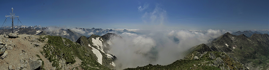 Alla croce di vetta del Corno Stella (2620 m), nuvoloso in Val Brembana , sereno sulle alte cime orobiche